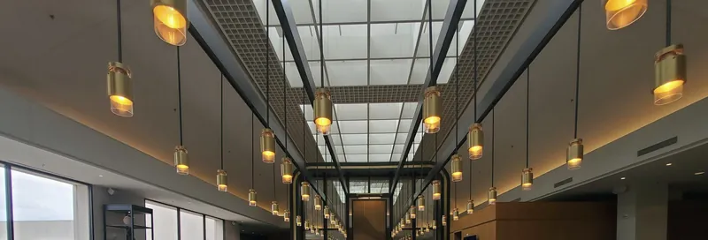 Lobby hotelu z mosiężnymi lampami pod przeszklonym dachem